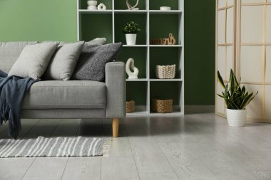 Şık oturma odasında yumuşak yastıklı gri kanepe.