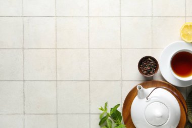 Çay demliği, çay fincanı ve fayans zemininde limon ile güzel bir kompozisyon.