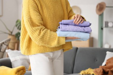 Evde bir yığın temiz giysi tutan genç bir kadın.