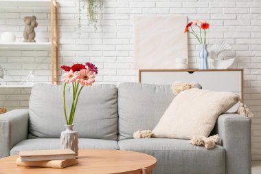 Vazodaki güzel Gerbera çiçekleri ve oturma odasındaki masada kitaplar.