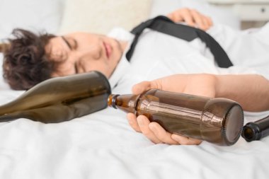 Sarhoş genç iş adamı yatakta yatıyor. Alkolizm kavramı