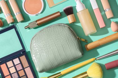 Yeşil arka planda kozmetik çanta ve makyaj ürünleri