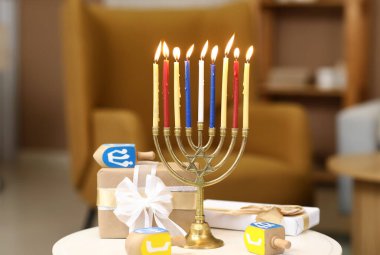 Yanan mumlar, hediye kutuları ve masandaki dreidelarla, yakın plan. Hanuka kutlaması