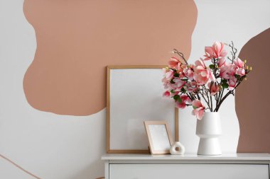 Çerçeveli çekmeceler ve odadaki renkli duvarın yanında manolya çiçekleri. Yakın çekim.