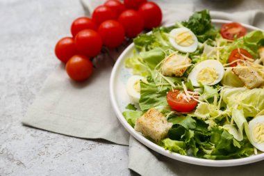 Lezzetli Sezar salatası ve gri arka planda domatesler, yakın plan.