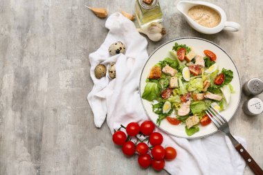 Lezzetli tavuklu Sezar salatası ve gri arka planda malzemeler.