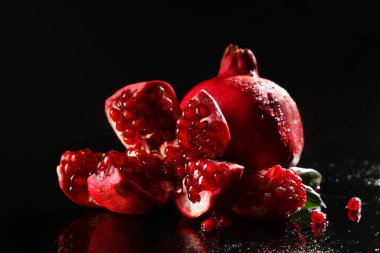 Siyah zemin üzerinde lezzetli olgun nar parçaları, yakın plan.