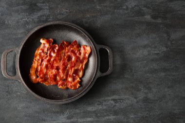 Siyah arka planda kızarmış pastırma pastırmalı kızartma tavası.