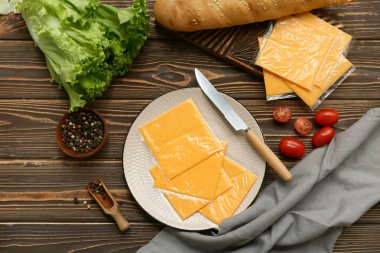 Lezzetli işlenmiş peynir dilimleri, biber ve ahşap masada taze sebzelerle dolu bir tabak.