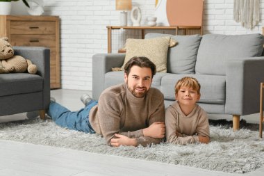 Babası ve küçük oğlu oturma odasında yerde yatıyor. Babalar Günü.