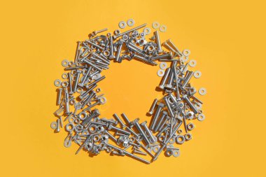 Turuncu arka planda farklı musluk cıvataları, vidalar ve krom fındıklardan yapılmış çerçeve