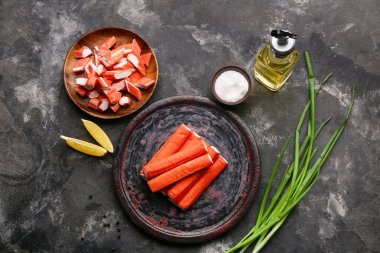 Lezzetli yengeç çubuklu tabaklar, siyah arkaplanda limon ve yeşil soğan parçaları