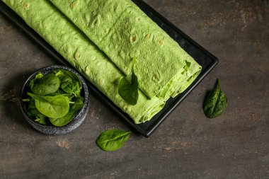 Yuvarlak yeşil lavaş ve siyah grunge arka planda ıspanak tabağı.