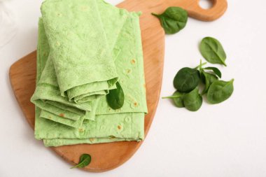 Tahta tahtada taze lavaş ve beyaz arka planda ıspanak var.