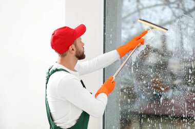 Odada cam sileceği olan bir erkek işçi.