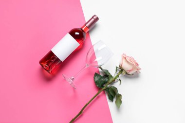Renkli arka planda güzel bir gül ve cam olan bir şişe pembe şarap.