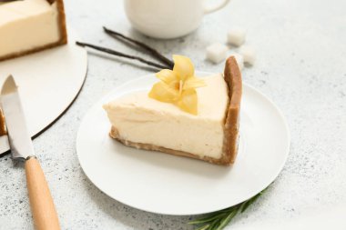 Vanilya çiçekli bir tabak tatlı cheesecake ve beyaz arka planda çubuklar.