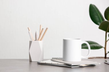 Ofisteki kalem tutacağının yanındaki masada beyaz seramik bardak.