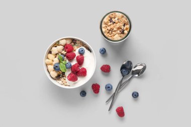 Beyaz arka planda sağlıklı mısır gevreği, yoğurt ve böğürtlen kâsesi.