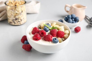 Beyaz arka planda sağlıklı mısır gevreği, yoğurt ve böğürtlen kâsesi.