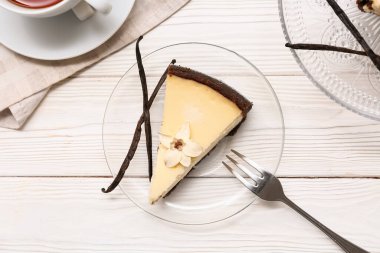 Beyaz ahşap arka planda tatlı vanilyalı cheesecake ile cam tabak