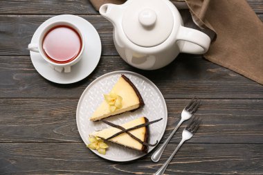 Bir tabak vanilyalı cheesecake ve siyah ahşap zemin üzerinde çay.