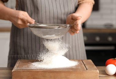 Mutfaktaki masada un elleyen bir kadın.