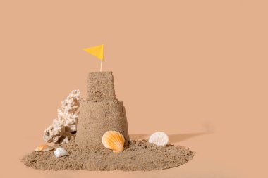 Güzel kumdan kale, bayrak ve bej arka planda deniz kabukları.