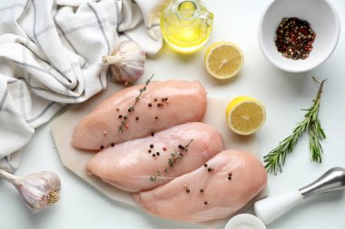 Çiğ tavuk göğsü ve beyaz arka planda farklı baharatlar olan tahta.