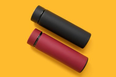 Sarı arka planda farklı modern termoslar