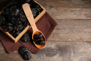 Tahta arka planda kurutulmuş kuru erikli kutu ve kaşık.