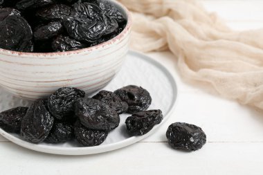 Beyaz ahşap arka planda kuru erikli tabak ve kase.