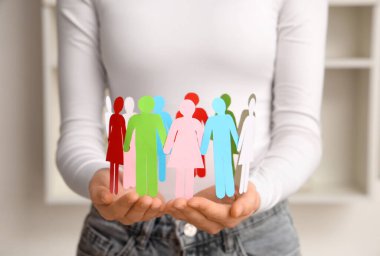 Elinde kağıt insan figürleri tutan bir kadın. Çeşitlilik ve kapsama kavramı