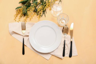 Altın çatal bıçak takımı ve sarı arka planda mimoza çiçekleri olan güzel bir masa.