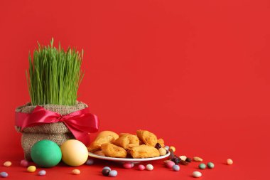 Lezzetli baklavalı yeşil buğday otları, yumurtalar ve kırmızı zemin üzerinde renkli şekerler. Nowruz Bayram kutlaması