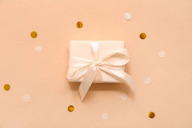 Kahverengi arka planda hediye kutusu ve konfeti.