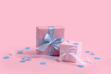 Yılan balıklı hediye kutuları ve pembe arka planda konfeti.