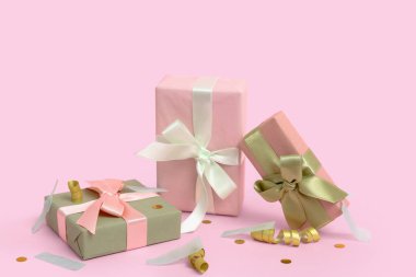 Yılan balıklı hediye kutuları ve pembe arka planda konfeti.