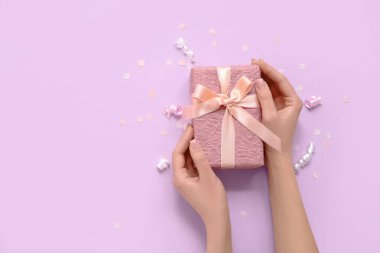 Hediye kutusuyla kadın elleri ve leylak arka planda yılan.