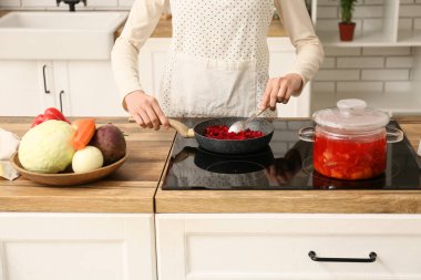 Mutfakta sebze kızartan genç bir kadın, yakın plan.