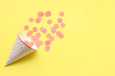 Sarı arka planda parti şapkası ve konfeti
