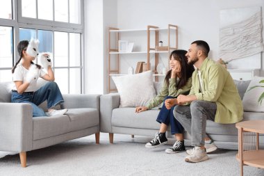 Kedi maskeli dörtlü kız ve ailesi evdeki koltuklarda oturuyor.