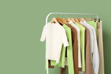 Odadaki yeşil duvarın yanında asılı giysilerle dizilin.