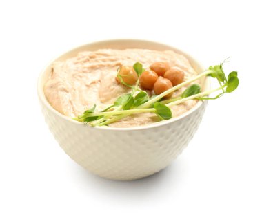 Beyaz zemin üzerinde nohut ve mikro yeşil olan lezzetli humus kasesi.