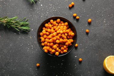 Siyah arka planda lezzetli kızarmış nohut, limon ve biberiye kâsesi.