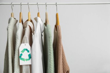 Beyaz arkaplanda asılı geri dönüşüm etiketli giysiler
