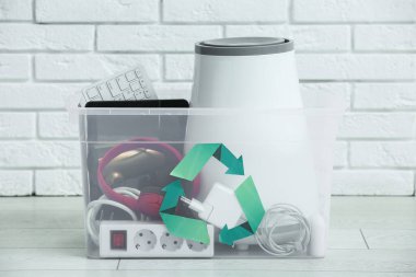 Beyaz tuğla duvarın yanında geri dönüşüm için elektronik atık içeren konteyner
