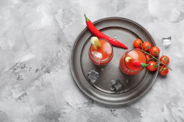 Kırmızı biberli, kerevizli ve gri arkaplanlı buzlu Bloody Mary kokteyli.