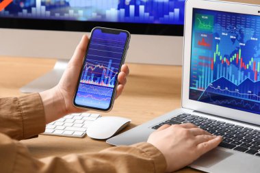 Ofisteki masada cep telefonu ve dizüstü bilgisayarla çalışan kadın tüccar, yakın plan.