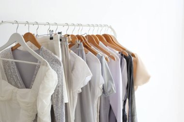 Rack with stylish female clothes near light wall, closeup